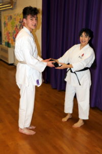 (Click to Enlarge) Sensei Shahinaz presenting William wit his Black Belt after passing brilliantly his Shodan Exam at the JKA England National Course, February 2020! 